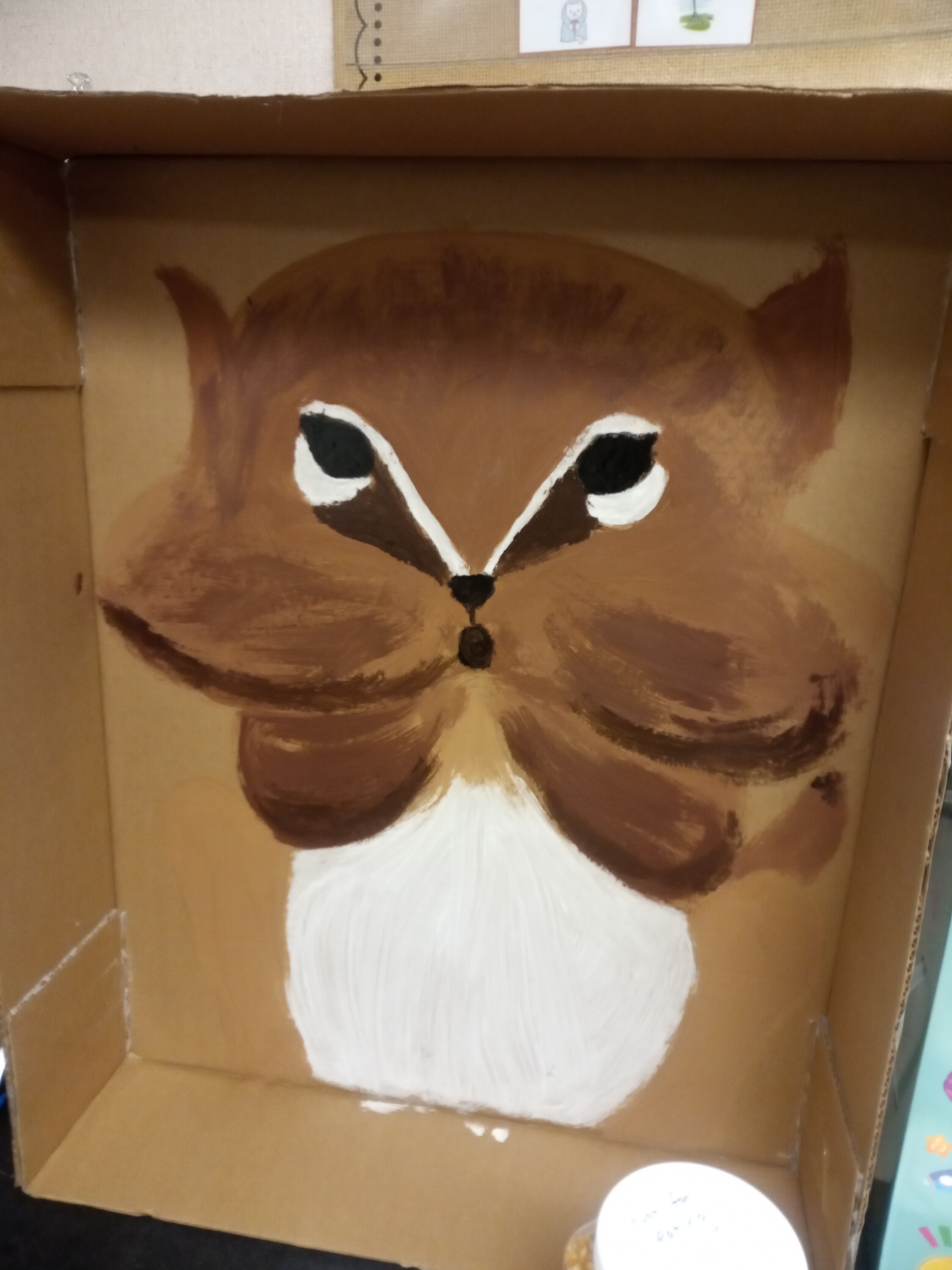 A painted chipmunk in a large cardboard box.