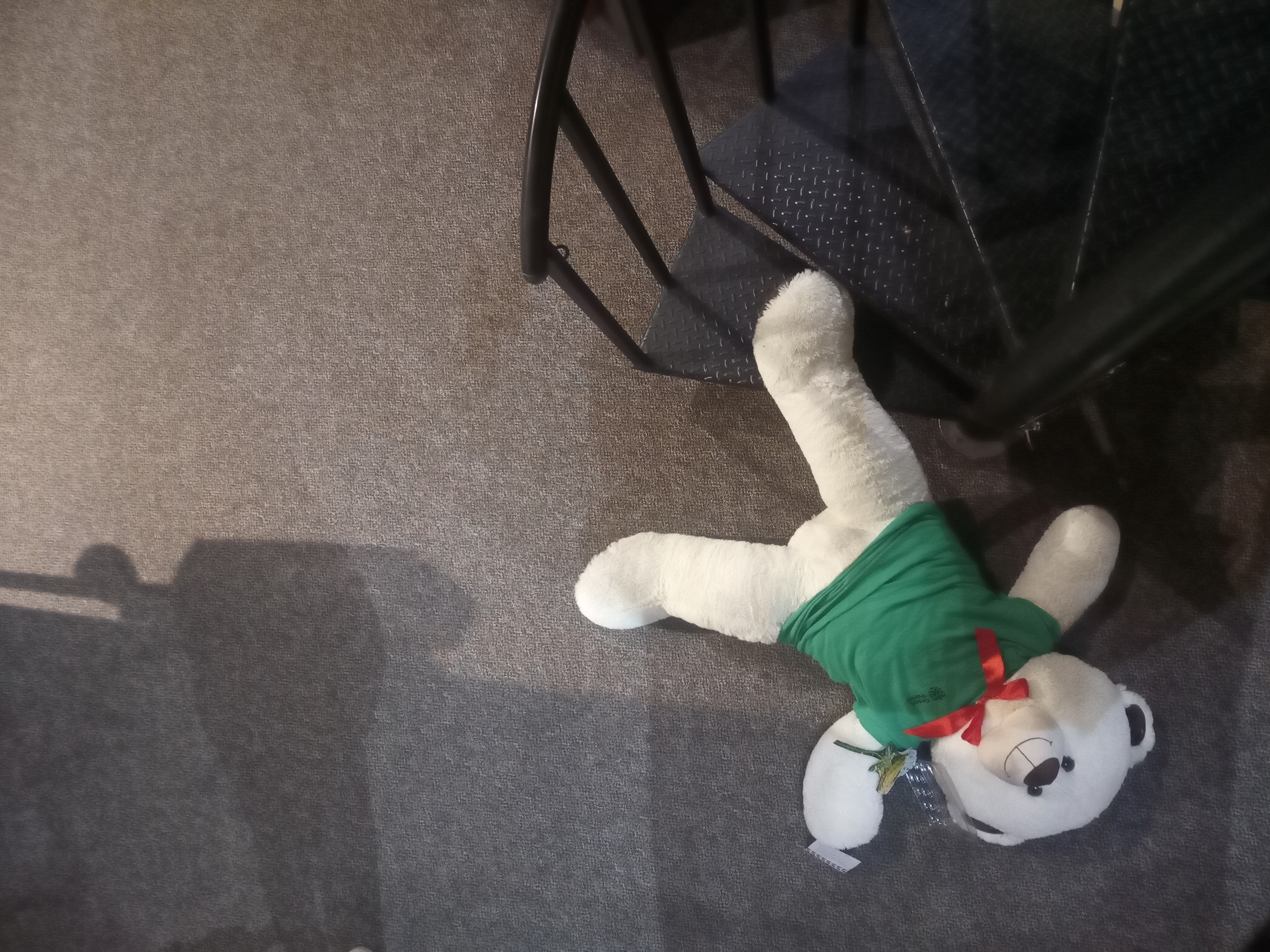 A large, white teddy bear laying sprawled out at the bottom of a spiral staircase.